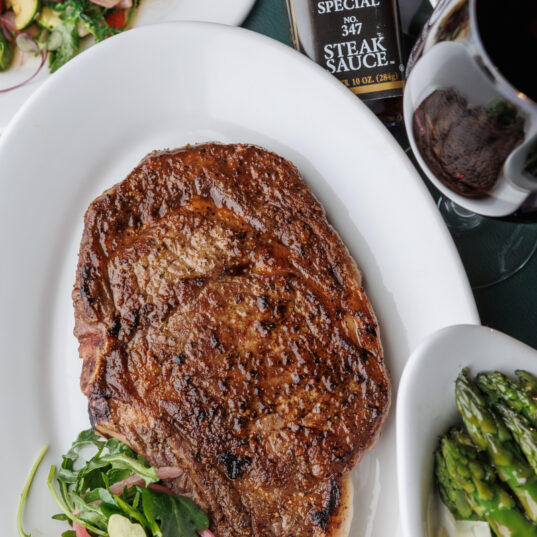 cooked steak with a side salad plated next to some asparagus
